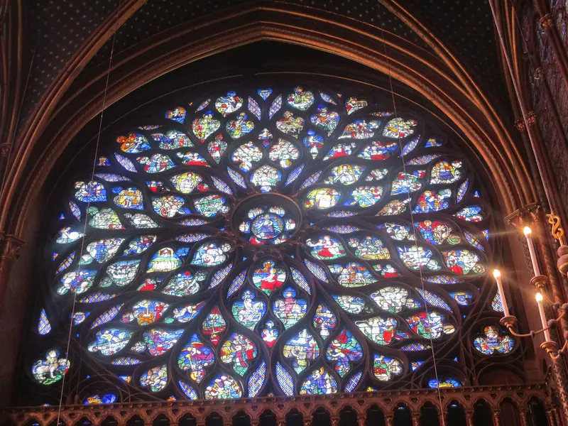 The west rose window of the Sainte-Chapelle's upper chapel in stained glass, with candle holders at the right edge of the frame