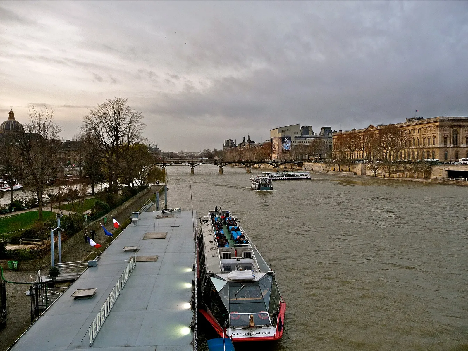 Vedettes du Pont Neuf pier and a sightseeing boat at the Square du Vert Galant, with the Louvre quay beyond, overcast late afternoon